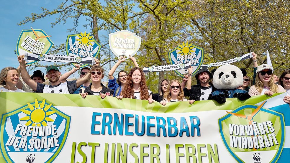 Demonstrierende halten ein Banner und Schilder in die Höhe, darunter eine Person im Pandakostüm. Foto: Michael Ukas