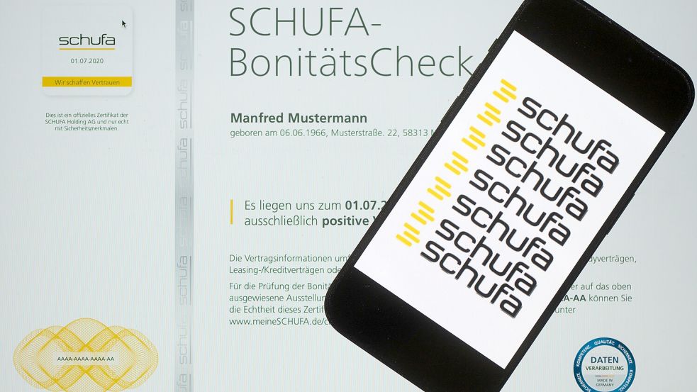 Wie viel Macht hat die Schufa über einen Kredit? Ein Smartphone mit dem Logo der Wirtschaftsauskunftei Schufa liegt auf einem Display mit einem Musterdokument eines Schufa-Bonitätszertifikats. Foto: Sebastian Kahnert/dpa