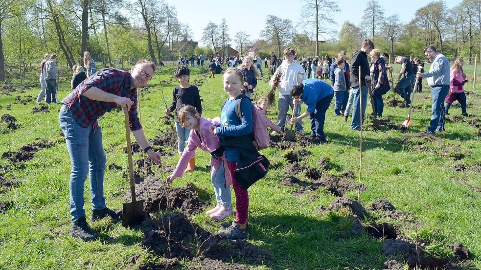 Hier entsteht ein Wald: Mira und Aileen von der Sundermannschule setzen gemeinsam mit Lehrer Sebastian Wöste junge Schösslinge in die Erde. Insgesamt beteiligten sich an der Pflanzaktion für den Albrecht-Weinberg-Wald am Rhauderfehner Untenende 58 Schülerinnen und Schüler der Grundschule sowie 55 Zwölftklässler des Albrecht-Weinberg-Gymnasiums. Foto: Astrid Fertig