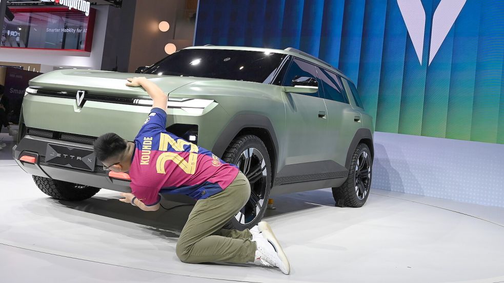 So sieht er aus, der VW-Stromer für gut 10.000 Euro: Ein Influencer kniet hier am Freitag, 24. April 2026, vor dem Jetta X der Volkswagen-Marke Jetta während der „Auto China 2026“. Foto: Johannes Neudecker/dpa