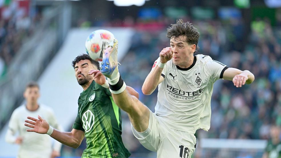 Hoch das Bein: Der Gladbacher Philipp Sander (r) geht gegen Wolfsburgs Mohamed Amoura beherzt zur Sache. Foto: Swen Pförtner/dpa