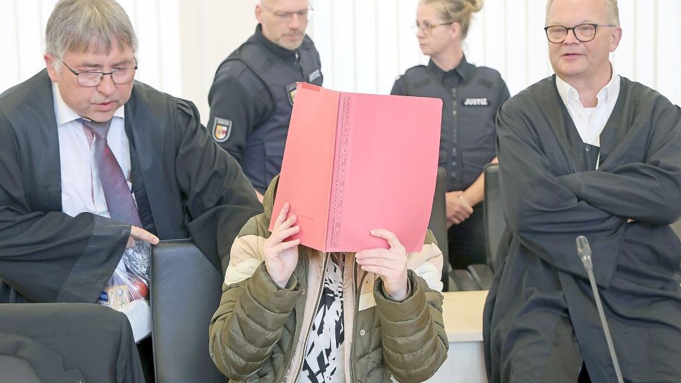 Die Angeklagte sitzt mit Aktendeckel vor dem Gesicht zwischen ihren Verteidigern Andreas Ohm (l-r) und Thomas Löcker. Foto: Bernd Wüstneck