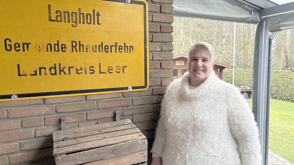 Ein Foto aus dem Januar 2025, Andrea Meiners steht in Langholt auf ihrer Terrasse neben dem Ortsschild. Zu dem Zeitpunkt war sie wenige Wochen als Ortsbürgermeisterin im Amt. Foto: Horst Kruse/Archiv