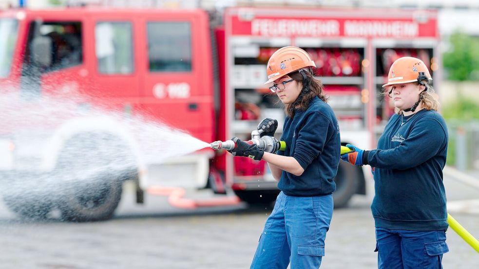 Ilias (links) und Annabella, Mitglieder der Jugendfeuerwehr in Mannheim, halten bei einer Übung einen Feuerwehrschlauch in den Händen. Foto: Uwe Anspach
