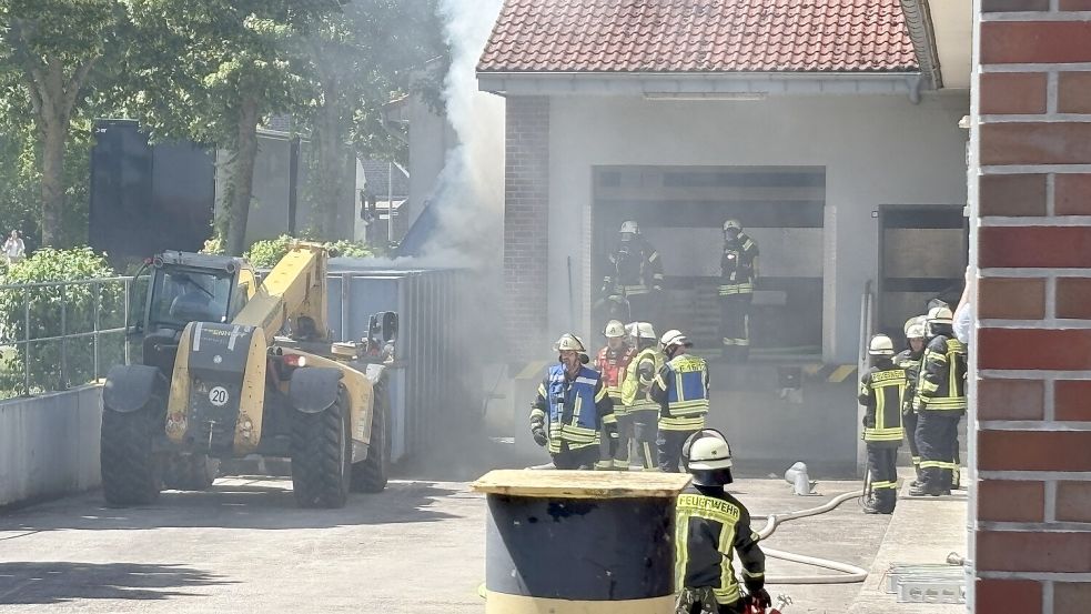 Die Feuerwehr bekam Unterstützung von einer nahegelegenen Baustelle. Ein Mitarbeiter zog mit schwerem Gerät den Container vor. Anschließend konnten die Einsatzkräfte das brennende Papier besser löschen. Foto: Carsten Ammermann