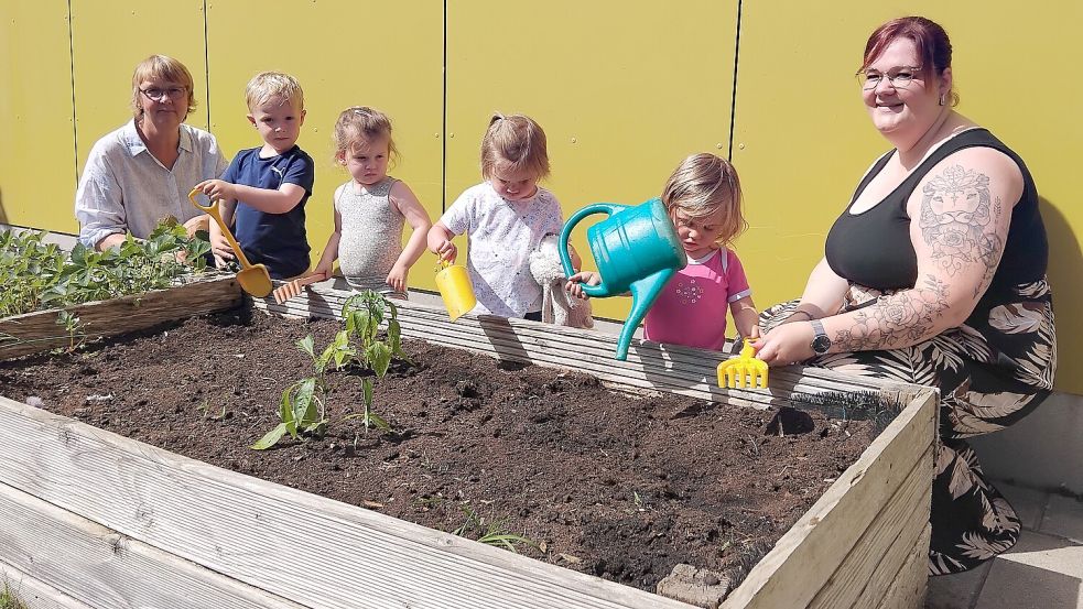 Erzieherin Sabine Harms (von links), Jonah, Marit, Marla, Eetje und Erzieherin Sandra Harders haben am alten Hochbeet Spaß am Gärtnern. Foto: Clarissa Scherzer