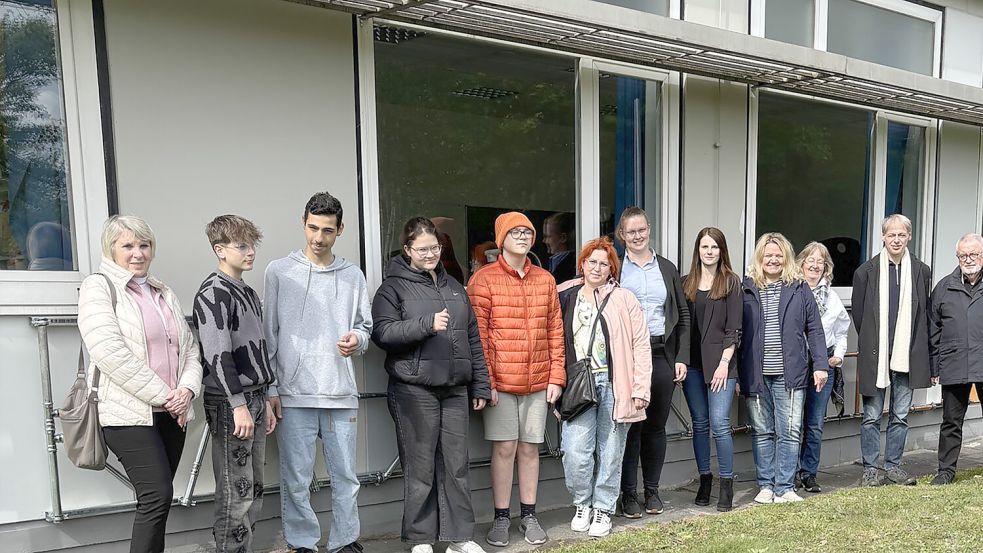 Gemeinsamer Abschluss vor dem neuen Schulschriftzug: Die beteiligten Schüler Maximilian Rjazancev, Abdul Aziz Alshekh Othman, Ilana Schäfer und Olexij Maleryk sowie Vertreter von Schule, Firma Natelberg, Ortsbürgermeister Jörg Furch, Eltern und die Generationen-Werkstatt beim Termin an der Erich-Kästner-Schule in Westrhauderfehn. Foto: Horst Kruse