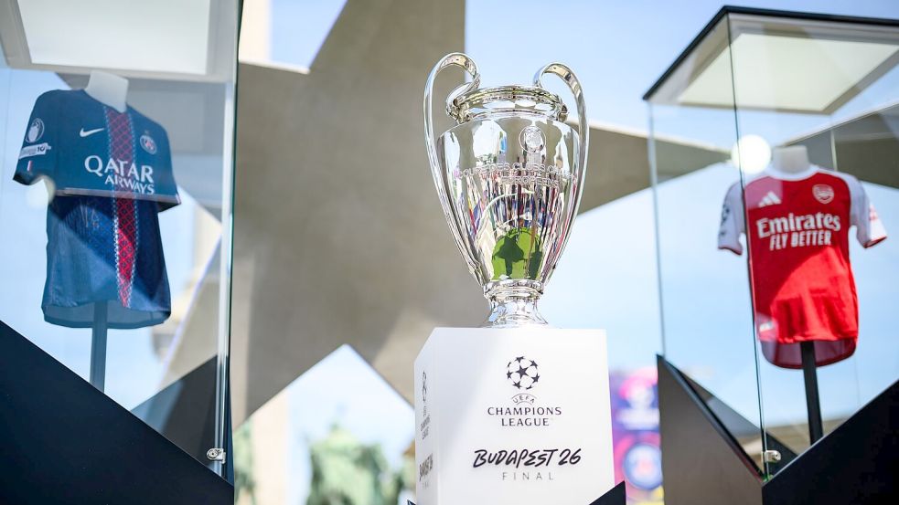 Der Pokal der Champions League steht zwischen den Trikots der Finalteams Paris Saint-Germain und FC Arsenal. Foto: Tom Weller