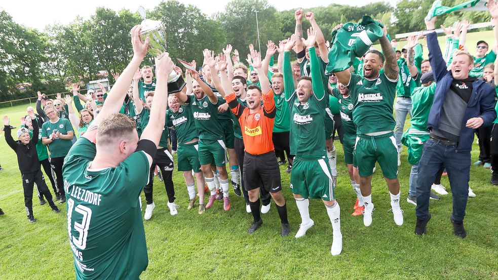 Da ist das Ding: Leezdorf-Kapitän Renke Harms präsentiert den Kreispokal Mitspielern und Fans. Foto: Jens Doden/ Emden