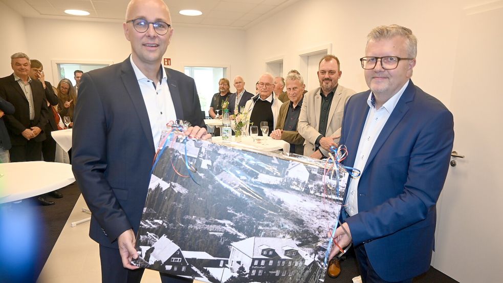 Westoverledingens Bürgermeister Theo Douwes (rechts) übergab Guido Mülder, Vorstandsmitglieder der Ostfriesischen Volksbank in Ihrhove, zur Wiederöffnung ein Bild. Dies zeigt eine Luftbildaufnahme der Raiffeisenbank Ihrhove aus dem Jahr 1958. Foto: Holger Weers