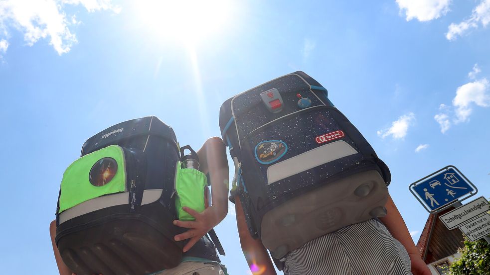 Zwei Kinder laufen mit ihren Schulranzen im Sonnenschein. Unter bestimmten Voraussetzungen können Kinder bei großer Hitze zu Hause bleiben. Foto: Karl-Josef Hildenbrand/DPA