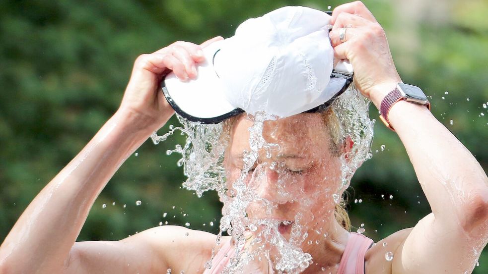 Eine Läuferin beim Hamburger Halbmarathon erfrischt sich an einer Wasserstelle. (Symbolbild) Foto: Markus Tischler/dpa