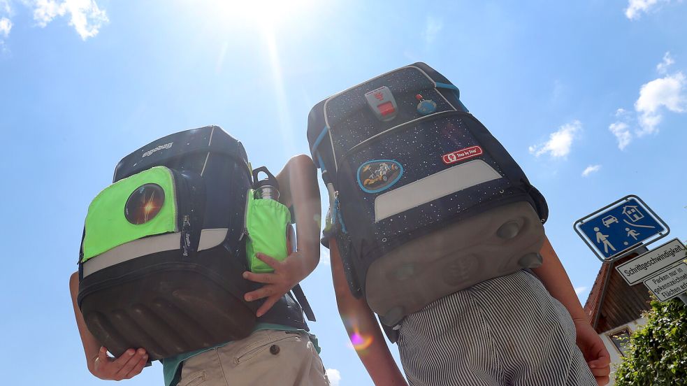 Zwei Kinder laufen mit ihren Schulranzen im Sonnenschein. Unter bestimmten Voraussetzungen können Kinder bei großer Hitze zu Hause bleiben. Foto: Karl-Josef Hildenbrand/DPA