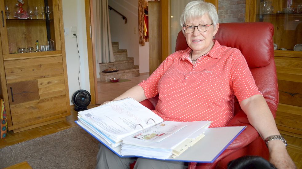 Ursula Buß-Anschütz sitzt in ihrem Wohnzimmer in Ostrhauderfehn. Auf den Knien hat die Seniorin einen Ordner, in dem sie ihre - bisher fruchtlose - Korrespondenz mit der EWE abgeheftet hat. Das Versorgungsunternehmen hat mitgeteilt, dass die Bearbeitung des Anliegens ihrer Kundin nicht angemessen gelaufen sei. Doch getan hat sich deshalb bei Ursula Buß-Anschütz weiterhin nichts. Foto: Astrid Fertig