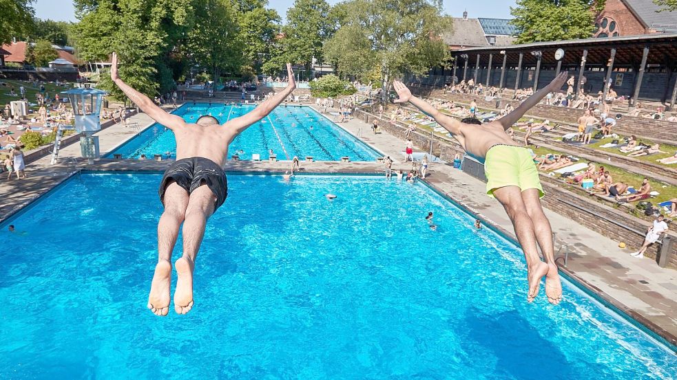 Zwei Männer springen vom Fünf-Meter-Turm in das Becken im Sommerfreibad Kaifu-Bad in Hamburg. Foto: Georg Wendt