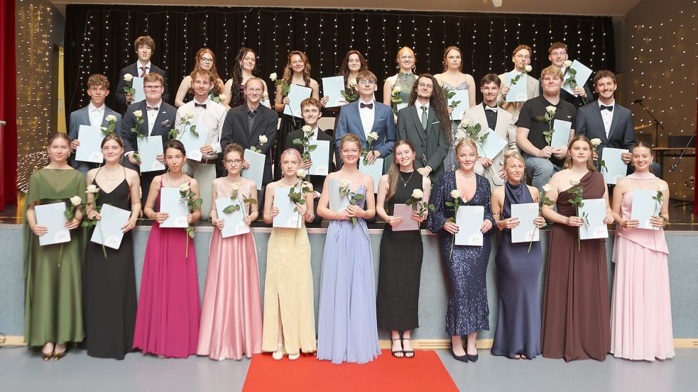 Glamourös wie Filmstars präsentieren sich die Abiturientinnen und Abiturienten der Freien Christlichen Schule Ostfriesland auf dem gemeinsamen Abschlussfoto. Bevor sie ihre Zeugnisse und Blumen in Empfang nahmen, schritten sie über den roten Teppich. Foto: FCSO / Rainer Haan