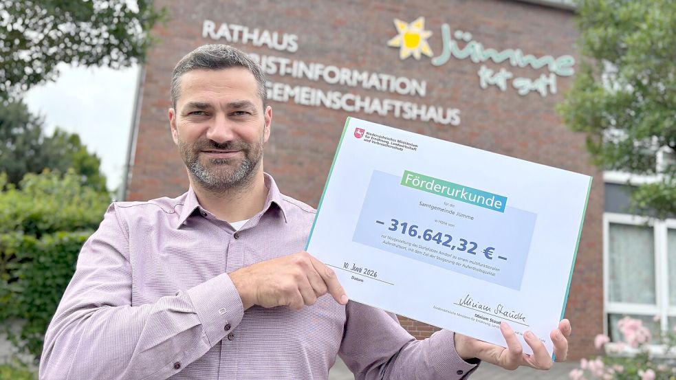 Christoph Busboom hält die Förderurkunde hoch, die die Samtgemeinde Jümme für die Neugestaltung des Amdorfer Dorfplatzes bekommen hat. Foto: Lars Löschen