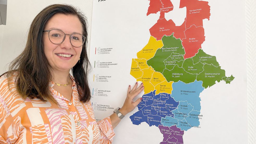 Neu im Pastoralen Raum Friesoythe: Ökonomin Rita Berndmeyer steht vor einer Karte, die die Pfarreien und Einrichtungen des Kirchengemeindeverbandes zeigt, hier gelb markiert. Foto: Claudia Wimberg