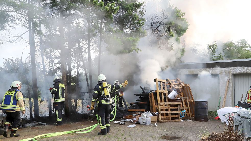 Mit mehreren Strahlrohren löschte die Feuerwehr den Brand an Hecke und Holzpaletten, die auf die Garage übergegriffen hatten. Foto: Hans Passmann