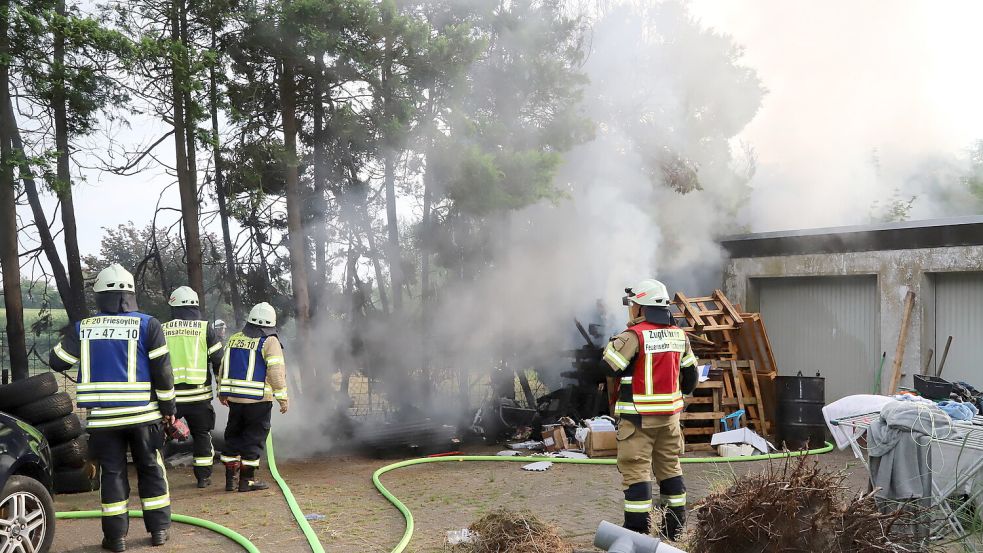 Mit mehreren Strahlrohren löschte die Feuerwehr den Brand an Hecke und Holzpaletten, die auf die Garage übergegriffen hatten. Foto: Hans Passmann