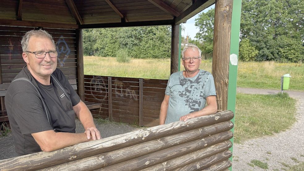 Horst Meyer (links) und Helwig Weber in der Schutzhütte am Hahnentanger See. Dahinter liegt das Areal, auf dem der Barfußpfad mit Bänken und kleinen Spielgeräten entstehen soll. Foto: Marion Janßen