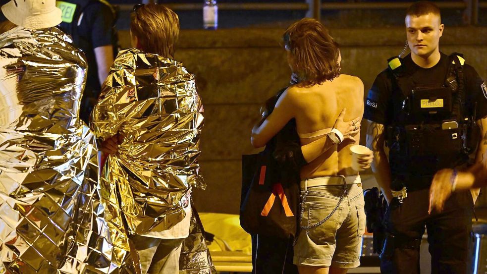 Menschen hüllen sich in Rettungsdecken und umarmen sich. Foto: Fabian Sommer/dpa