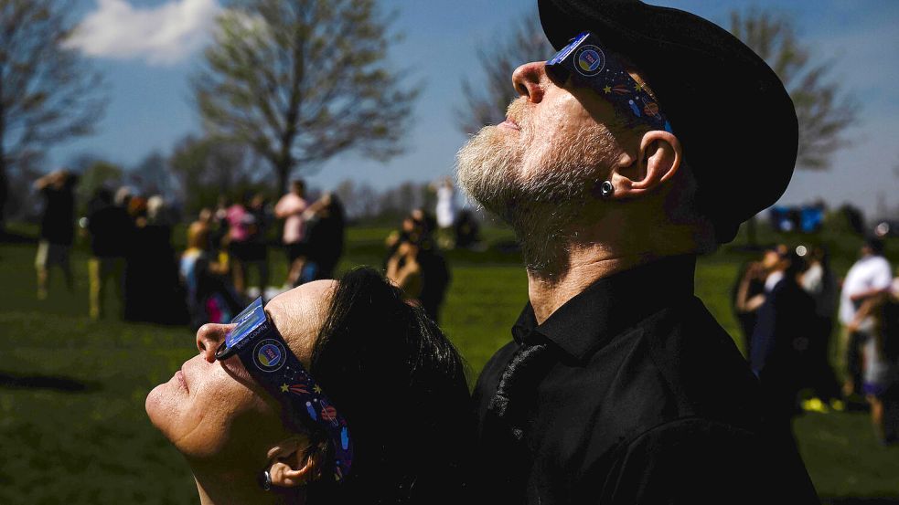 Mehrere Menschen schauen sich gemeinsam eine Sonnenfinsternis an. Symbolfoto: Jon Cherry/AP/dpa