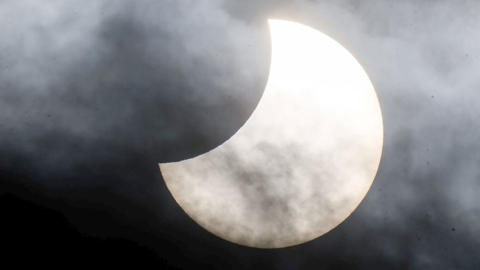 Eine partielle Sonnenfinsternis ist zwischen Wolken am Himmel zu sehen. (Archivbild) Foto: Julian Stratenschulte