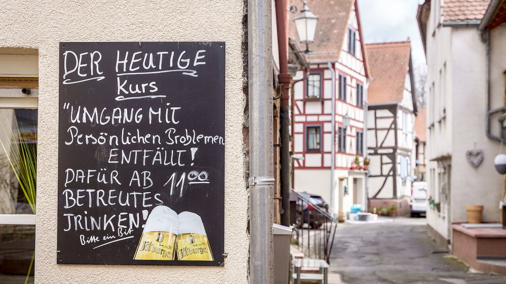 An der Mauer einer Gaststätte steht auf einer Tafel «Der heutige Kurs 'Umgang mit persönlichen Problemen' entfällt, dafür ab 11.00 Uhr betreutes Trinken». Foto: Frank Rumpenhorst/dpa