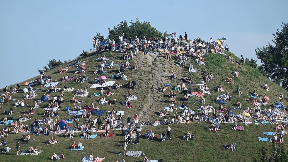 Erste Besucher bevölkern den Olympiaberg im Münchner Olympiapark, um von dort die partielle Sonnenfinsternis zu beobachten. Foto: Felix Hörhager