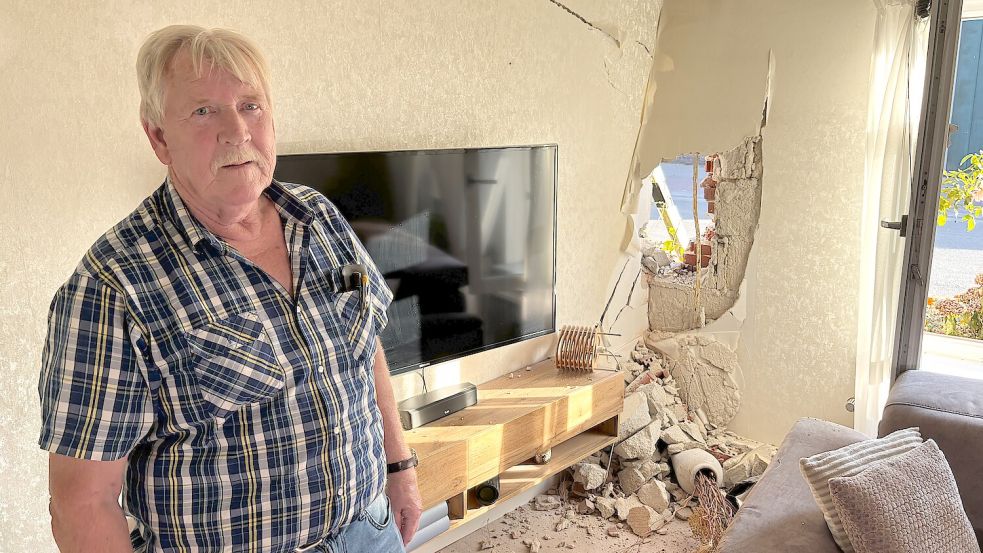 Anwohner Jann Fransen in seinem Wohnzimmer. Durch den Aufprall eines Treckers wurde die Außenwand schwer beschädigt. Foto: Hannah Weiden