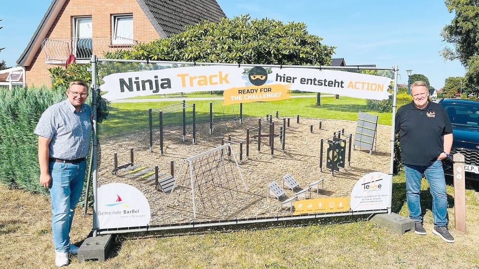 An der Marschstraße in Neuland entsteht ein neuer Kinderspielplatz als „Ninja-Park“. Bürgermeister Nils Anhuth (links) und Ludger Wieborg haben bereits die Werbetafel aufgestellt. Foto: Hans Passmann