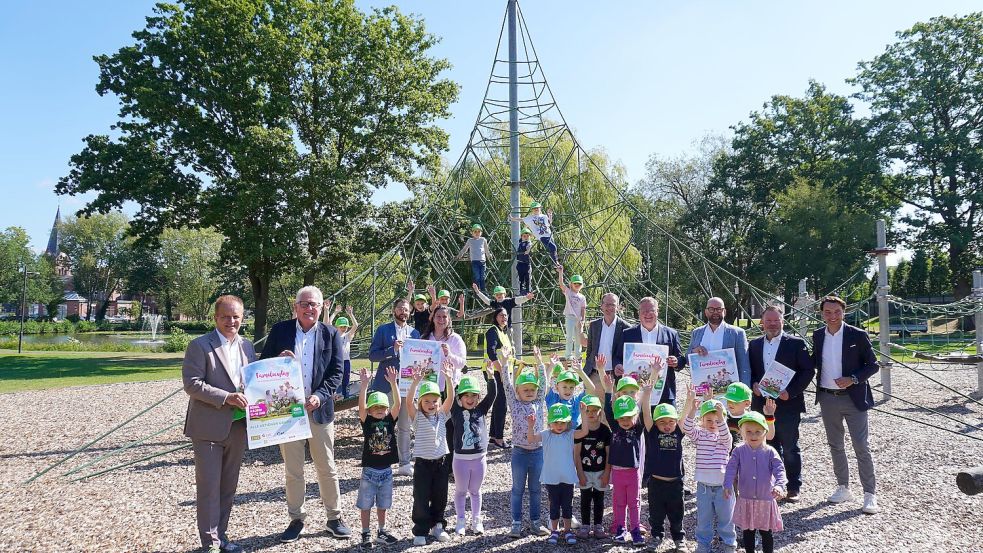 Vorfreude im Dorfpark Bösel: Kita-Kinder und Vertreter von Gemeinde, Verbund und Sponsoren präsentieren das Programm für den OM‑Familientag (von links):  Bürgermeister Hermann Block, Gemeinde Bösel, Gerhard Niemann, EWE Netz GmbH, Dennis Schröder, Filialleiter Bösel, LzO, Birgit Beuse, Projektleitung Verbund Oldenburger Münsterland, Susanne Wittich, Kindergarten St. Raphael,   Volker Raker, Direktor Privatkundengeschäft LzO, Landrat Tobias Gerdesmeyer, Präsident Verbund Oldenburger Münsterland e. V., Landrat Johann Wimberg, Vize-Präsident Verbund Oldenburger Münsterland e. V., Stefan Nording, Orga-Team der Gemeinde Bösel, Jan Kreienborg, Geschäftsführer Verbund Oldenburger Münsterland e. V. sowie Kita-Kinder der St. Raphael-Kindergartens aus Bösel.   Foto: Verbund OM/Franziska Feldhaus