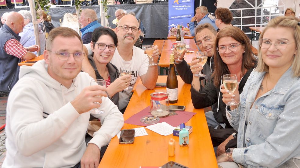 Besucher des Weinfests am Alten Hafen in Weener blicken gut gelaunt in die Kamera. Foto: Bodo Wolters