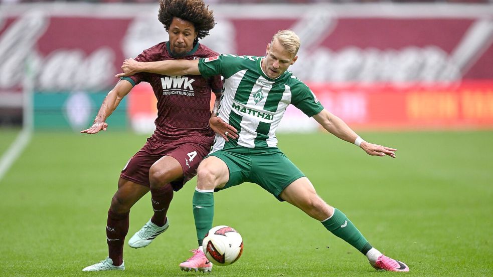 Im Zweikampf: Han-Noah Massengo vom FC Augsburg (l) und der Bremer Marco Grüll. Foto: David Inderlied/dpa