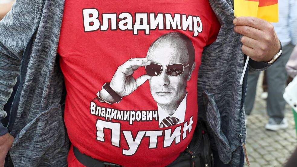 Im sachsen-anhaltischen Naumburg posiert ein Mann bei einer AfD-Kundgebung mit einem T-Shirt. Darauf ist Russlands Machthaber Wladimir Putin samt Foto und Namen in kyrillischer Schrift abgebildet. Foto: IMAGO/Karina Hessland