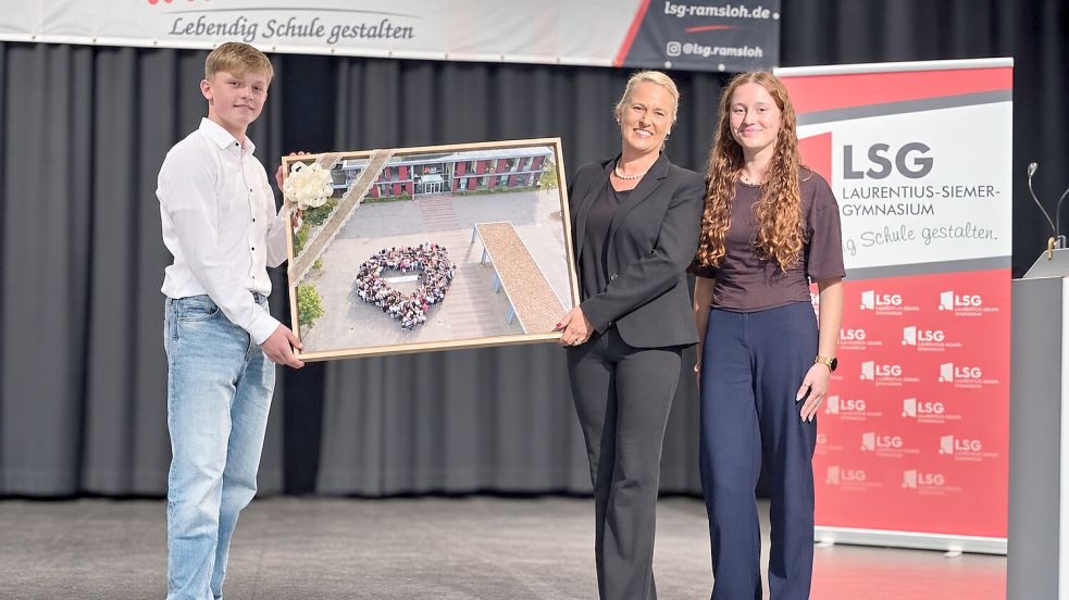 Lina Buß und Malte Wilkens überreichten der neuen LSG-Schulleiterin Maren Steinert ein Foto, für das sich die gesamte Schulgemeinschaft auf dem Schulhof in Form eines großen Herzens versammelt hatte. Foto: LSG