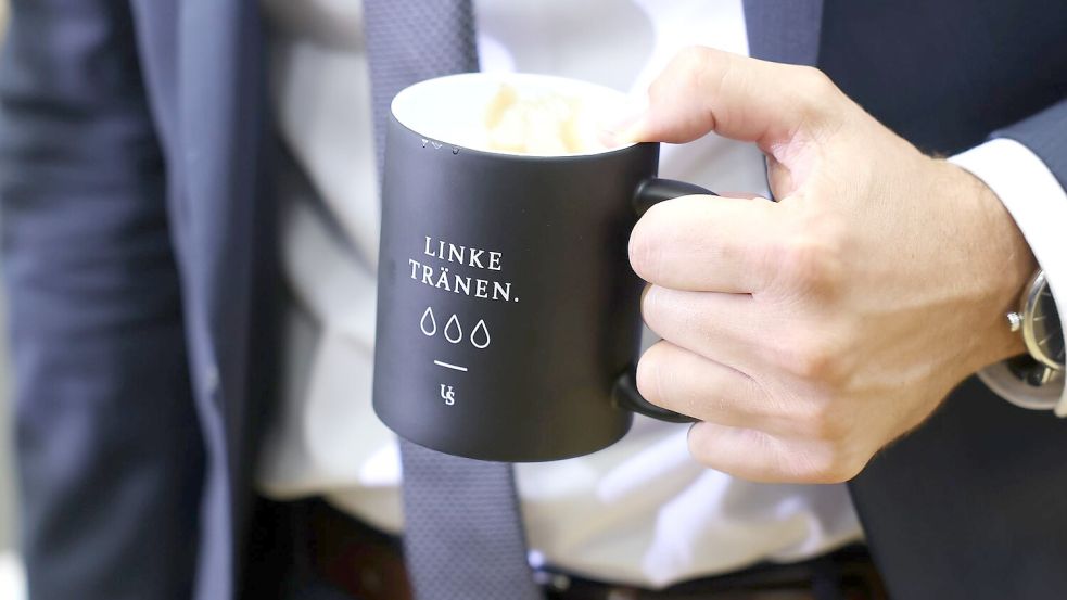 „Linke Tränen“ steht auf einer Tasse, mit der Ulrich Siegmund (AfD) zur konstituierenden Sitzung des Landtags von Sachsen-Anhalt kommt. Foto: Jan Woitas/dpa pool/dpa