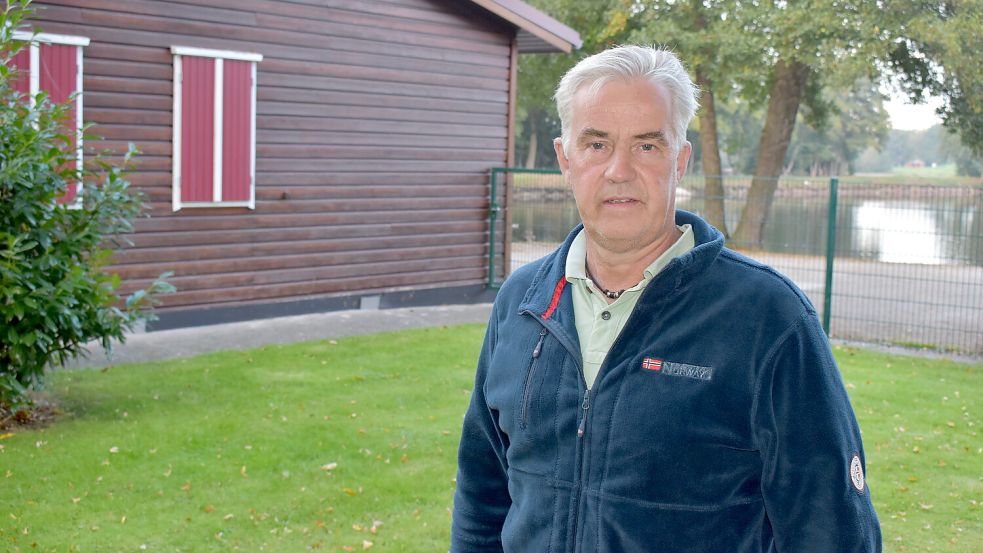 Dort, wo der Vorsitzende Torsten Kramer steht, soll die neue Geschäftsstelle des Fischereivereins Rhauderfehn gebaut werden. Links ist das Anglerheim zu sehen, im Hintergrund der Hahnentanger See. Foto: Henrik Zein