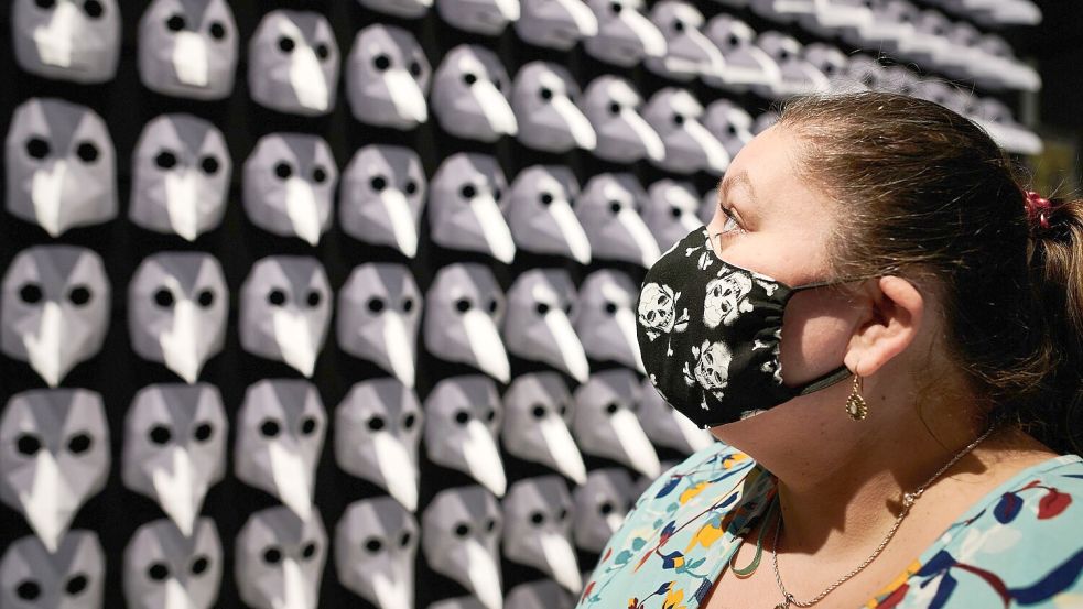 Eine Besucherin mit Mundschutz schaut sich in der Ausstellung „Pest – Eine Spurensuche“ ein Exponat aus 300 sogenannten Pestmasken an. Foto: Bernd Thissen/dpa